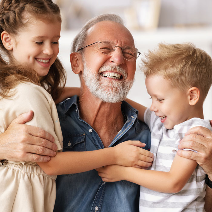 grandfather smiling with two grandchildren